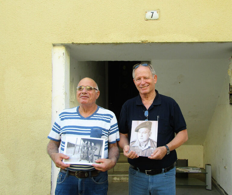 דב פז (מימין) ושלמה אשנגראו ז&quot;ל בפתח ביתם ברחוב הצנחנים עם תמונות אביהם (צילום: יעל הורוביץ)