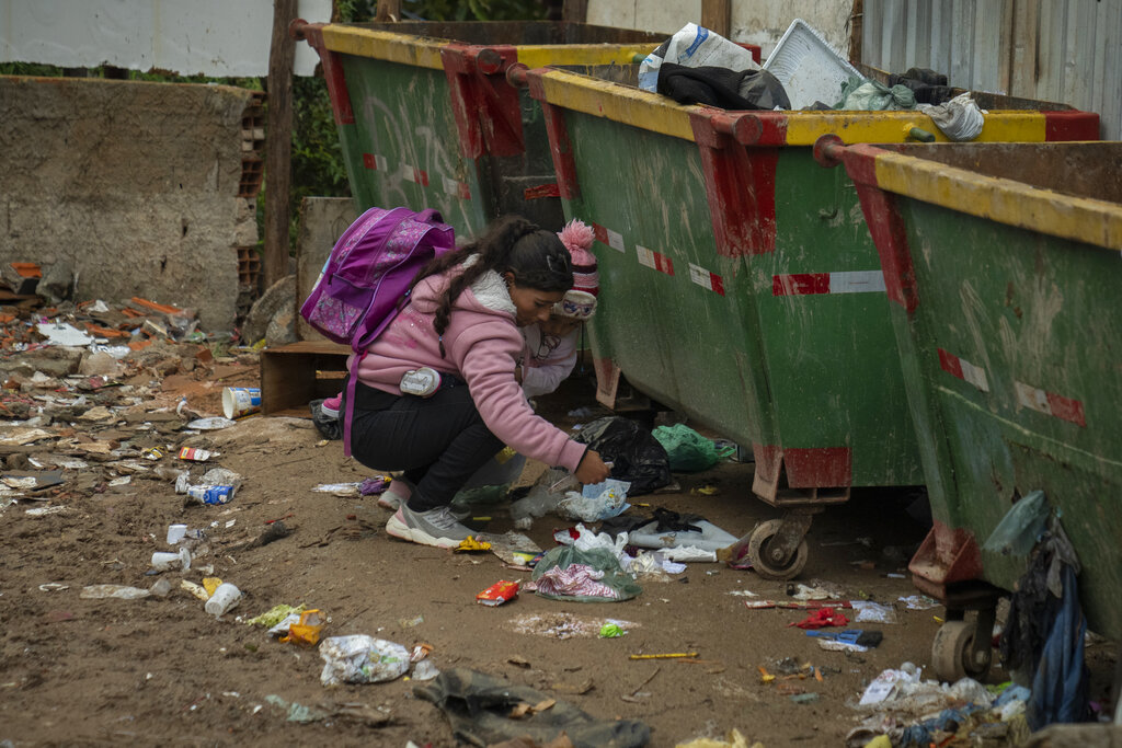 תלמידה מחטטת בפחי אשפה בברזיל. משקי בית עניים רבים במשבר חובות מתגלגל (צילום: AP Photo/Victor R. Caivano)