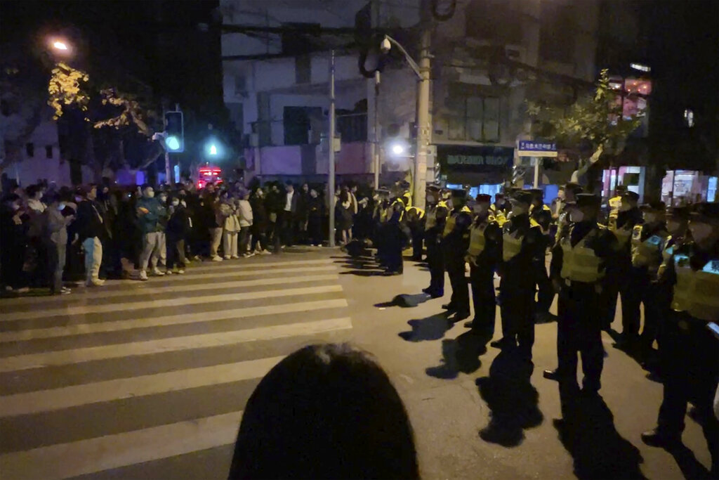 מפגינים מול שוטרים בסין: הפגנות חריגות פרצו ברחבי המדינה כתגובה להתמשכות סגרי והגבלות הקורונה (צילום: AP Photo)
