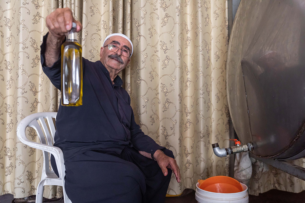 נג'יב אמיר עבדאללה עם בקבוק שמן זית טרי בבית הבד שלו בכסרא (צילום: כדיה לוי)
