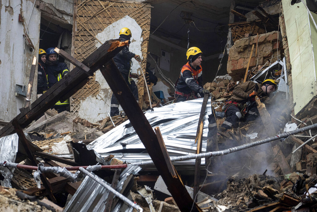 כבאים משירות החירום הלאומי באוקראינה פועלים בהריסות של בניין דירות שנפגע ממתקפת טילים רוסית בקעיר קריווי רייה באוקראינה, 16 בדצמבר 2022 (AP Photo/Evgeniy Maloletka)