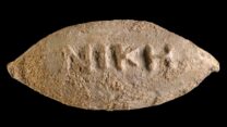 המילה "ניצחון" על גבי הקליע. (צילום: דפנה גזית, רשות העתיקות)