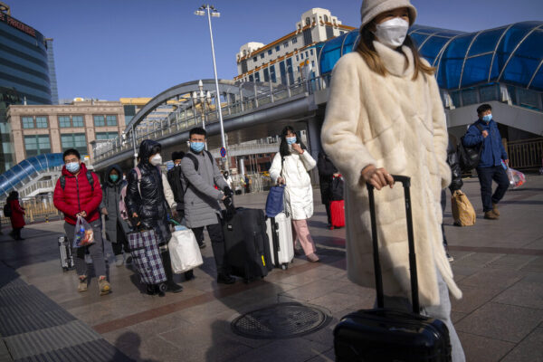 סינים חובשי מסכות בדרכם לתחנת הרכבת בביג'ין (צילום: מרק שייפלבוים/AP)