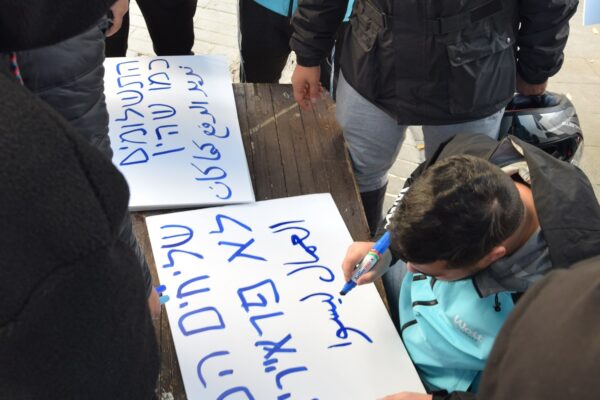 עובדי וולט מכינים שלטים בעברית ובערבית במחאה על תנאי העסקתם (צילום: אור גואטה)