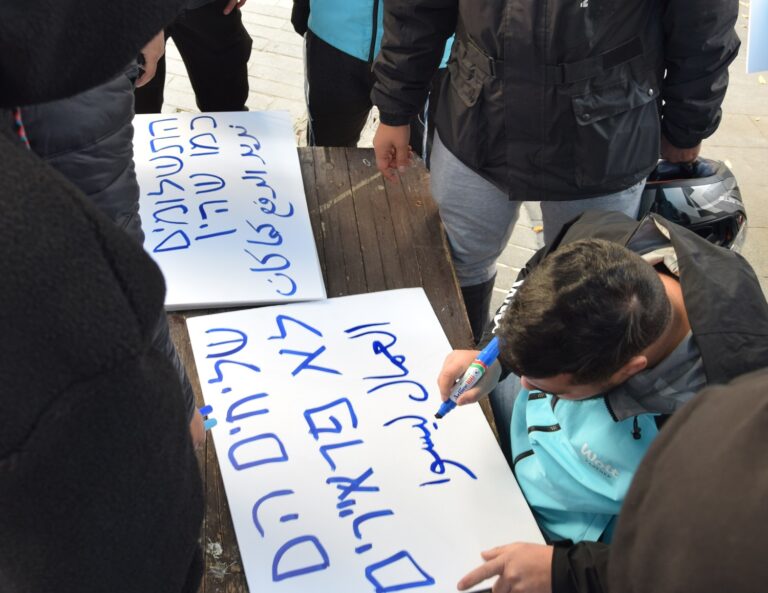 Wolt workers prepare signs in Hebrew and Arabic to protest their employment conditions. (Photo: Or Guetta)