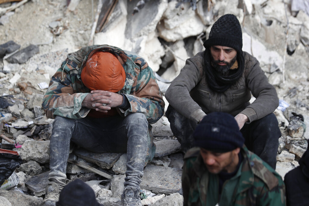 אנשים יושבים על הריסות הבניינים שקרסו בחאלב שסוריה, לאחר רעידת האדמה (צילום: AP/Omer Sandiki)