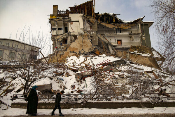 אנשים חולפים ליד בניין שקרס ברעידת האדמה במלטיה, טורקיה (צילום AP/Amara Gural)