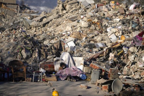 אדם ישן לייד הריסות בניין בדרום מזרח טורקיה. אלפים נותרו חסרי בית בעקבות רעידת האדמה בטורקיה ובסוריה (צילום: AP Photo/Khalil Hamra)