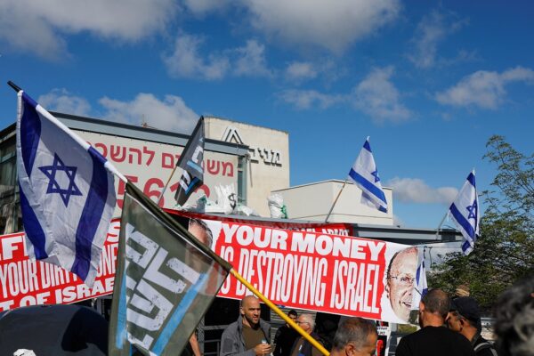A protest in front of the Forum Kohelet offices in Jerusalem, with a sign showing pictures of Jeffrey Yass and Arthur Danchik, the American billionaires who donate to the forum, with the caption "Your money is destroying Israel." (Photo: Reuters/Ammar Awad)