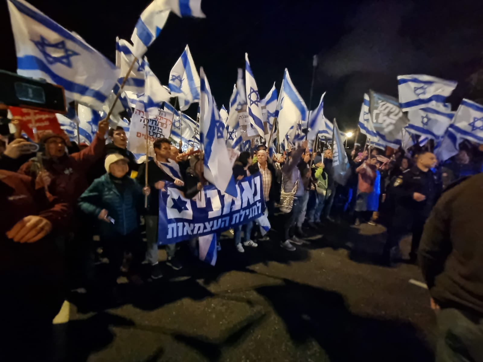 המפגינים מניפים דגלי ישראל ושלטים עם הכיתוב "נאמנים למגילת העצמאות" ו"חופשי בארצנו" (צילום: אילן פיגנבוים)