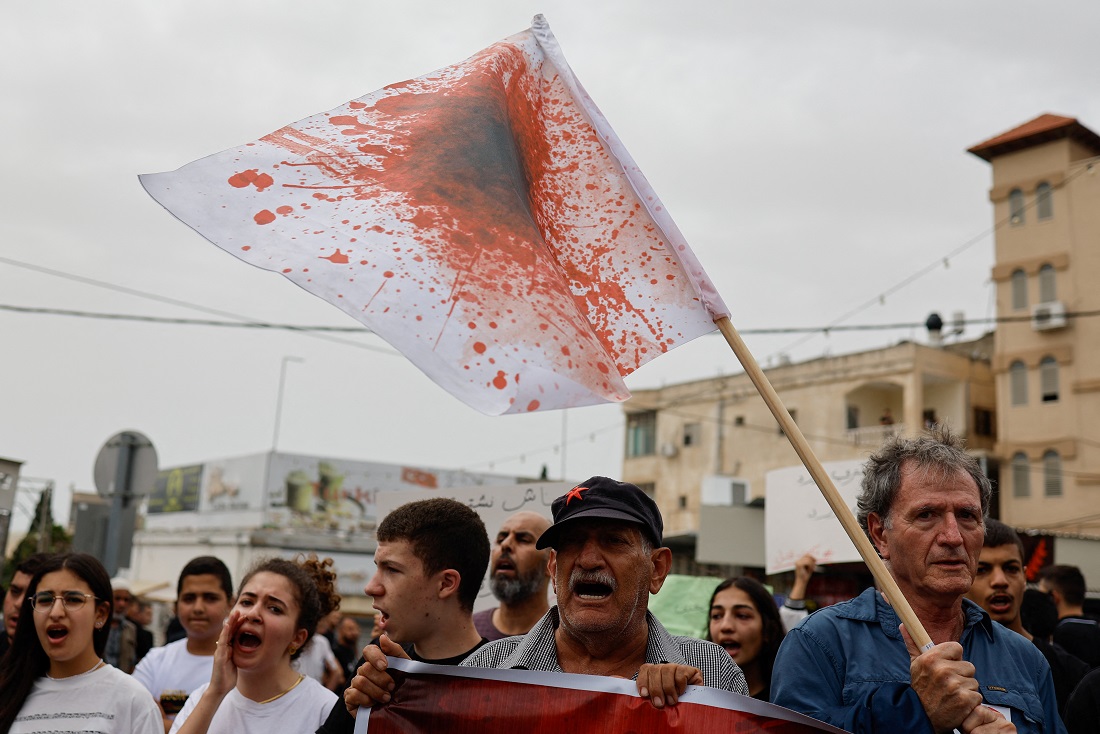 متظاهرون في الناصرة يرفعون علماً رُسمت عليه بقع دماء، وذلك أثناء مظاهرة احتجاجاً على الإجرام في المجتمع العربي ، وذلك بعد يوم من مقتل خمسة أشخاص في منشأة لغسيل السيارات في يافة الناصرة (تصوير REUTERS/Ammar Awad)