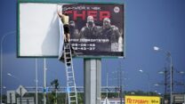 אדם מסיר שלט גיוס לכוח ואגנר בסנט פטרבורג (צילום: AP Photo)