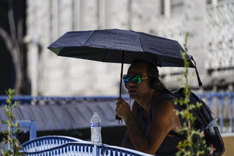 גבר משתמש במטריה כדי להימנע מהשמש בקליפורניה (צילום AP/ריאן סאן)
