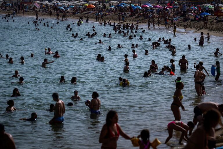 אנשים מתקררים על חוף הים בברצלונה. הטמפרטורות במדינה מגיעות ל-40 מעלות (צילום AP/אמיליו מורנאטי)