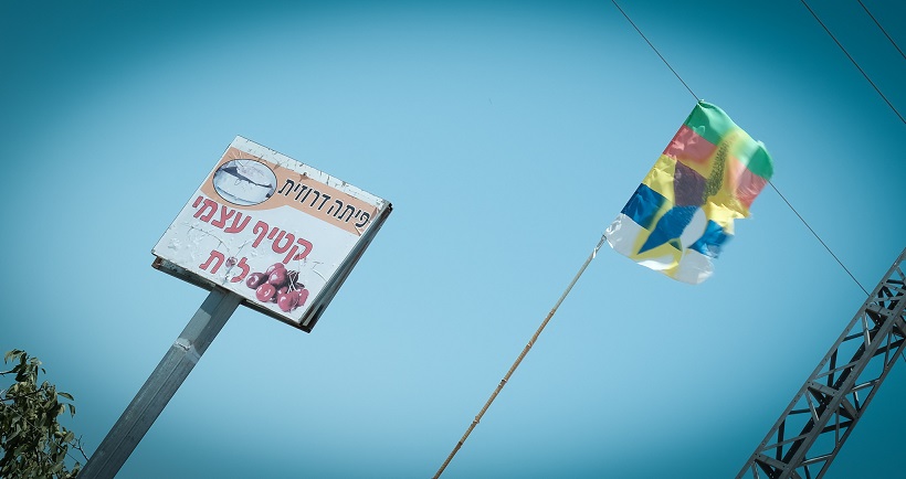 لافتة وعليها دعوة لقطف الكرز وراية الدروز بالقرب من مزرعة في شمال الجولان (تصوير: دافيد تابيرسكي)
