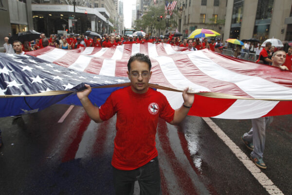 עובד עם דגל ארה"ב בהפגנה בלייבור דיי (צילום: AP Photo/Mary Altaffer, File)