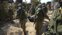 חיילים מוציאים גופות נרצחים מהטבח שביצעו מחבלי חמאס בכפר עזה (צילום: AP Photo/Erik Marmor)