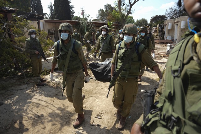 Soldiers remove the bodies of those killed in the massacre by Hamas terrorists at Kibbutz Kfar Aza. &quot;Our trauma is not over yet. Half of our community is missing&quot; (Photo: AP Photo/Erik Marmor).