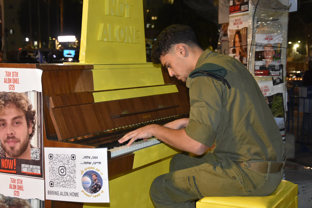 חייל מנגן על הפסנתר שהוצב לכבוד אלון אהל שנחטף לעזה (צילום: הדס יום טוב)
