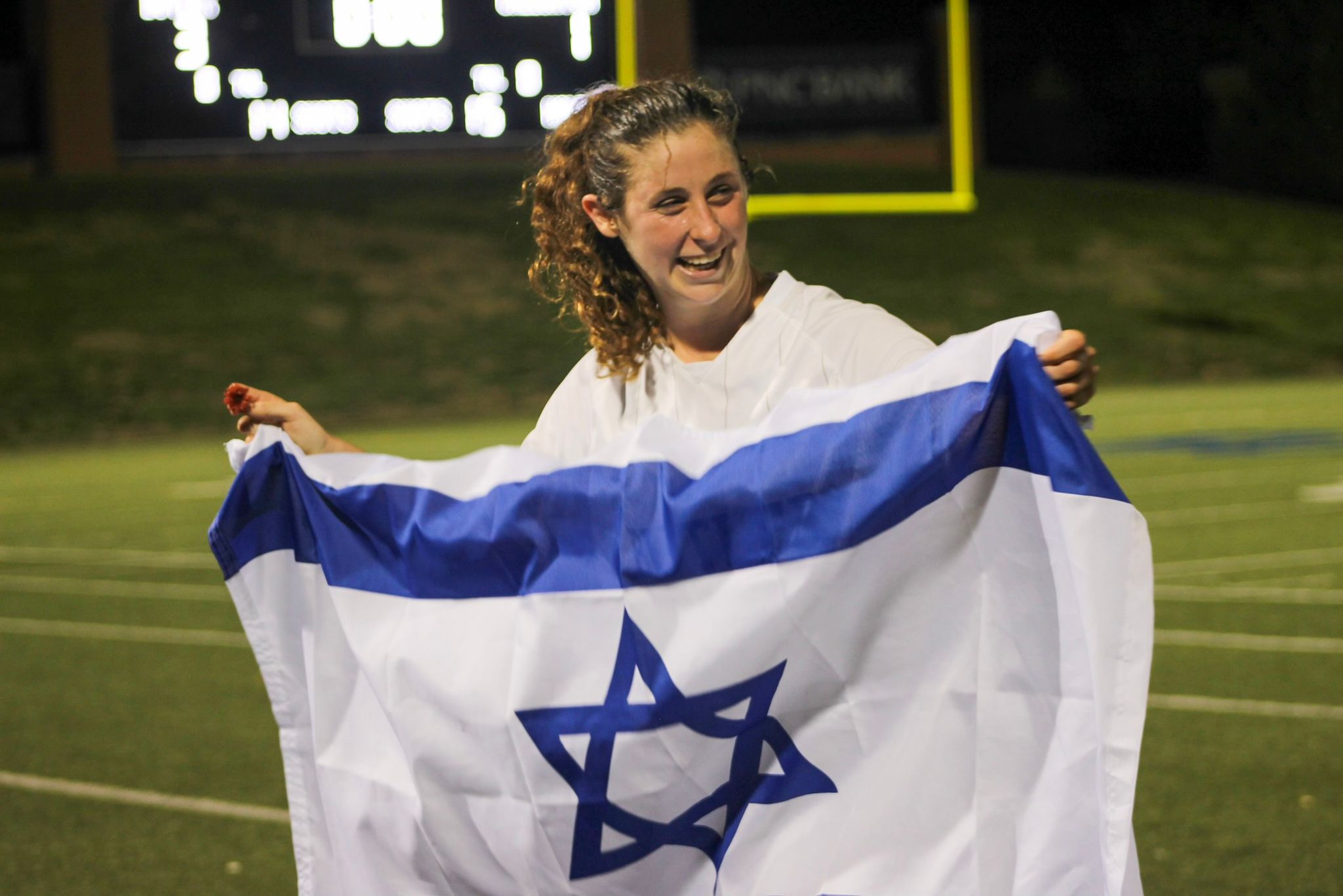 טליה זומר במדי אוניברסיטת באטלר, מניפה את דגל ישראל. &quot;בכל משחק מה-7 באוקטובר אני עולה למגרש במטרה לשחק הכי טוב שאני יכולה&quot; (צילום: Delaney Hudson)