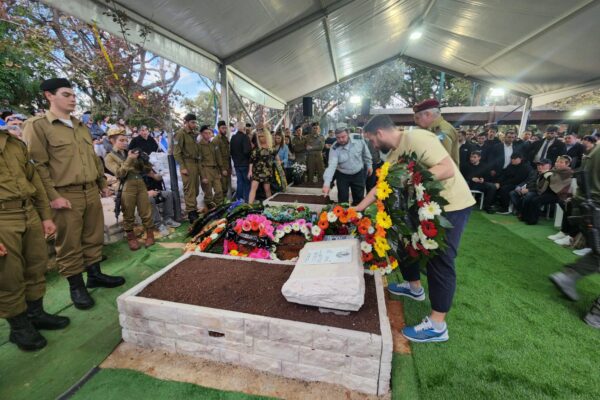 משתתפי הלוויה מניחים זרים על הקבר (צילום: דפנה איזברוך)