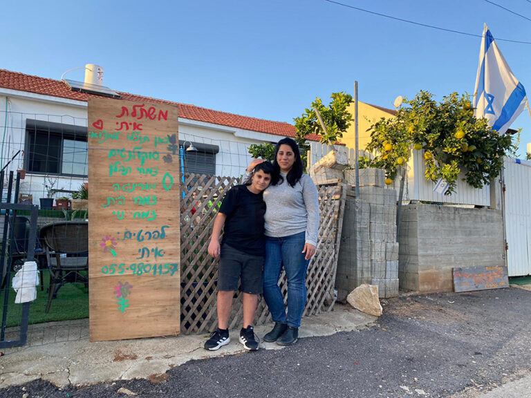 Itai and his mother Lilach at the entrance to their home next to the sign “Itai Nursery.” Lilach: “Some people only find what they love at the age of 40, but he has already found what makes butterflies in his heart.” (Photo: Yahel Farag)