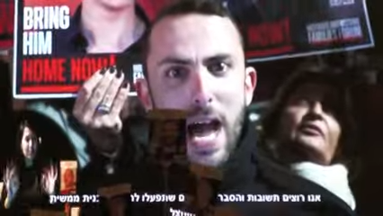 מור שוהם, אחיו של החטוף תל שוהם, מדבר בקיסריה עת דבריו מועברים בשידור חי לעצרת בכיכר החטופים (צילום מסך: מטה משפחות החטופים והנעדרים)