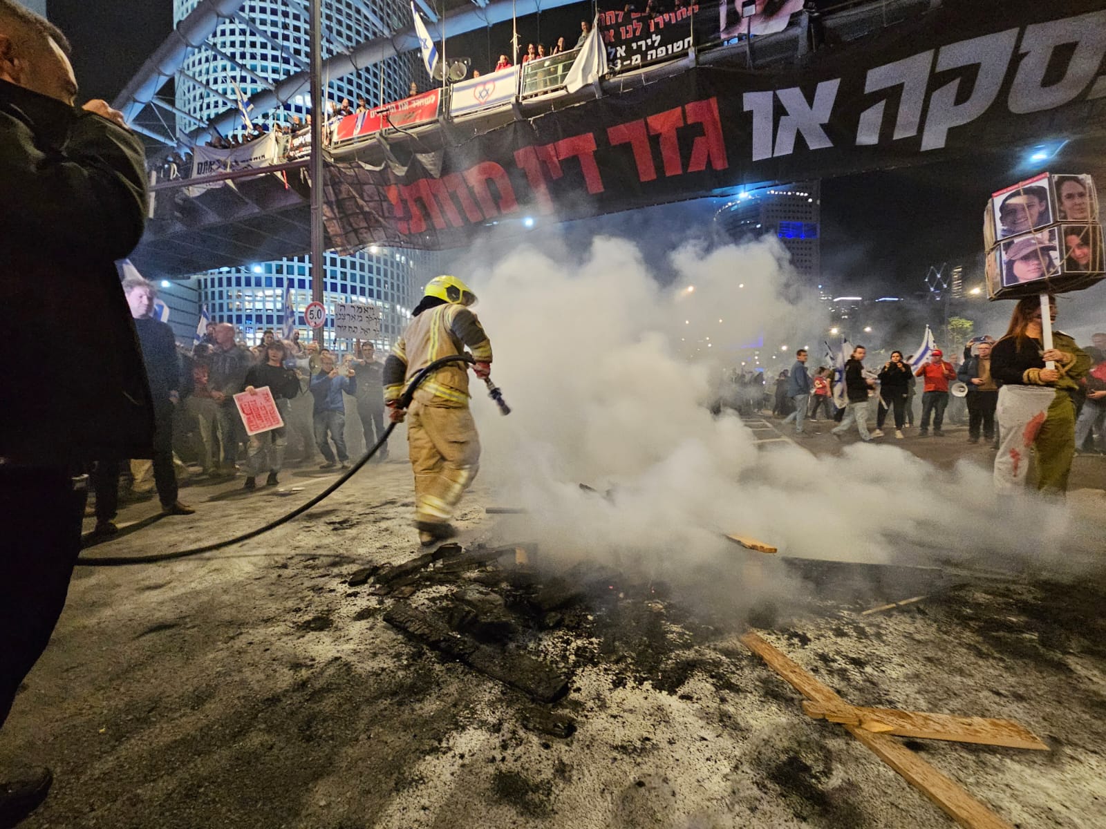כבאים מכבים מדורה שהבעירו מפגינים מול הקריה בדרישה מהממשלה לפעול לשחרור החטופים (צילום: דורון הבסי)