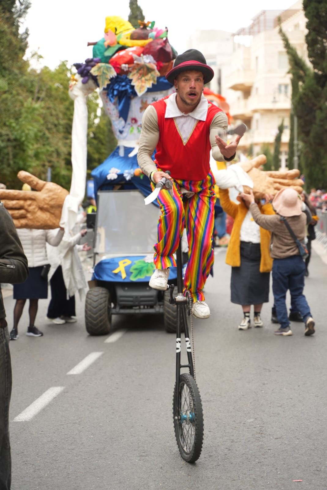 רוכב על חד אופן בתהלוכה, כשסמל מאבק החטופים על הרכב מאחור (צילום: דוברות עיריית ירושלים)