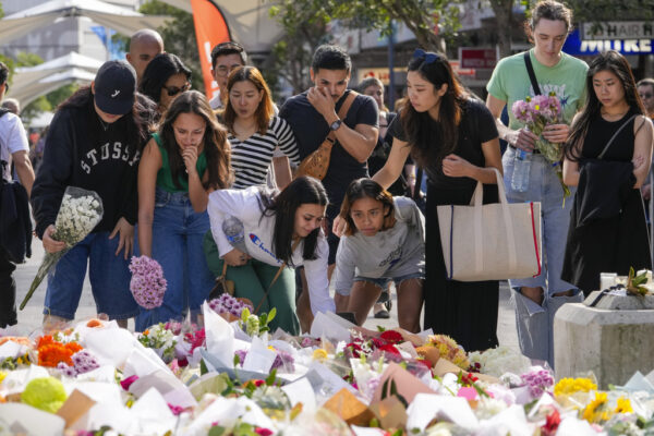 נשים מניחות זרים באנדרטה מאולתרת בזירת הפיגוע בסידני (צילום: AP Photo/Mark Baker)