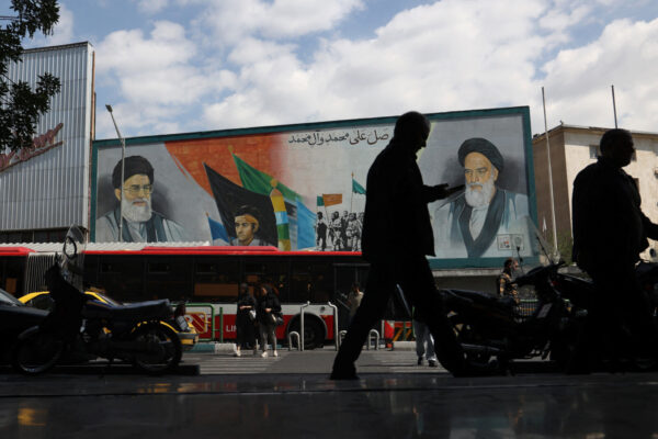 איראנים חולפים ליד ציור קיר של חומייני וחמינאי, 20 במאי 2024 (צילום: Majid Asgaripour/WANA (West Asia News Agency) via REUTERSY)