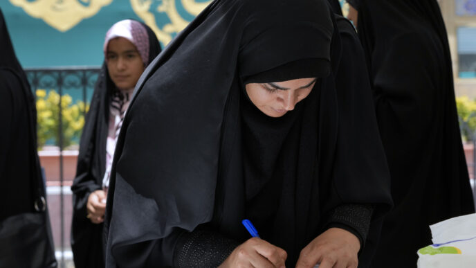 אשה ממלאת את טופס ההצבעה בבחירות לנשיאות איראן בסאינט סלה בטהראן (AP Photo/Vahid Salemi)