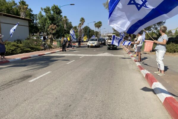 שתי שורות של אנשי הקיבוץ ותומכים עם דגלי ישראל ודגלים צהובים בדרך לאירוע הפרידה מיגב בוכשטב (צילום: יהל פרג')
