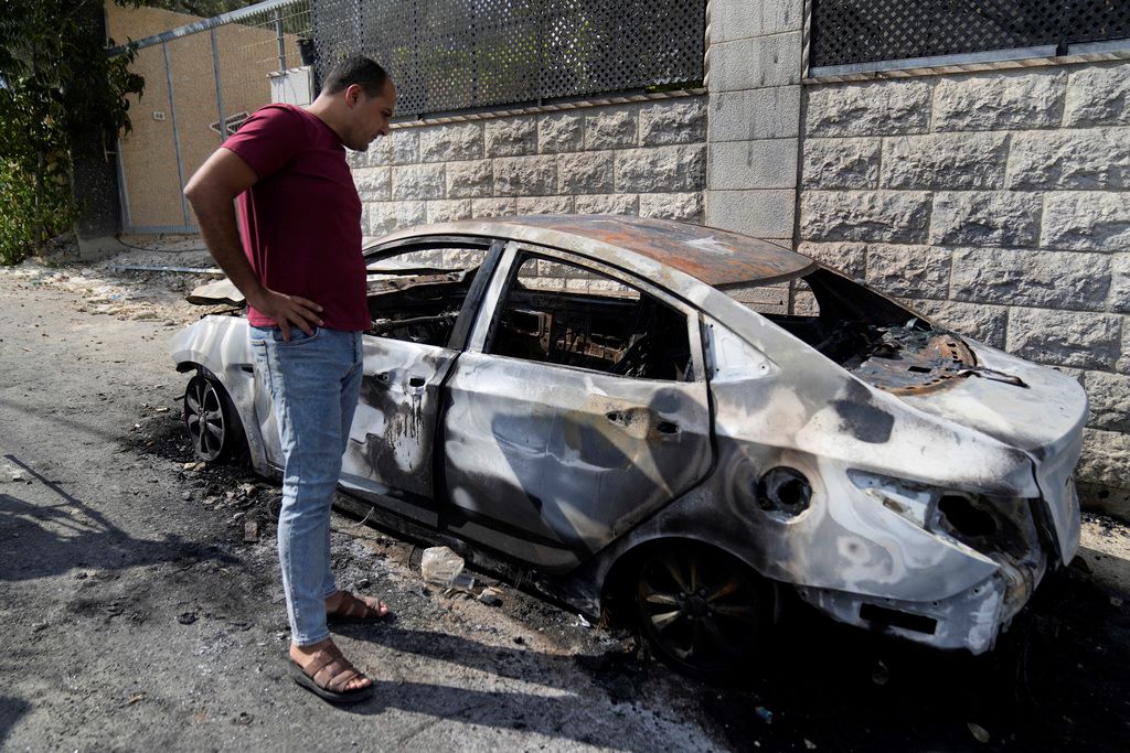 פלסטיני מביט ברכב שנהרס בהתפרעויות של עשרות יהודים בכפר ג'ית שבשומרון (צילום: AP Photo/Nasser Nasser)