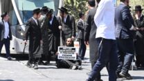 צעיר מהפלג הירושלמי חוסם את הרכבת הקלה בירושלים בהפגנה נגד גיוס חרדים. על השלט נכתב "צה"ל לא מגן על יהודים, אלא על הציונות" (צילום: אור גואטה)