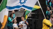 האלוף האולימפי בגלישת רוח תום ראובני ומדליסטית הכסף בהתעמלות אמנותית וקפטנית הנבחרת, רומי פריצקי, נושאים את דגל ישראל בטקס הסיום של המשחקים האולימפיים בפריז (צילום: הוועד האולימפי בישראל)