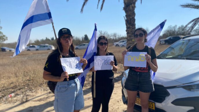 נערות מקיבוץ עין השלושה עם שלטי "סליחה" בכניסה לקיבוץ נירים, ביום הלווייתו של יגב בוכשטב ז"ל (צילום: יהל פרג')