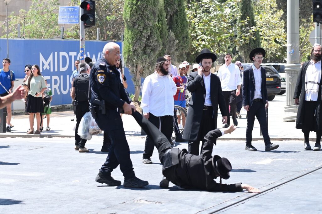 תנ"צ אמיר ארזני, מ"מ מפקד מחוז ירושלים, מושך ברגלו של מפגין ששוכב על המדרכה (צילום: אור גואטה) תנ"צ אמיר ארזני, מ"מ מפקד מחוז ירושלים, מושך ברגלו של מפגין ששוכב על המדרכה (צילום: אור גואטה)