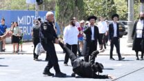 תנ"צ אמיר ארזני, מ"מ מפקד מחוז ירושלים, מושך ברגלו של מפגין ששוכב על המדרכה (צילום: אור גואטה)