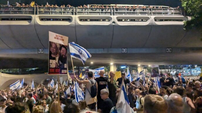 מפגינים למען שחרור החטופים חוסמים את נתיבי איילון בתל אביב, ומניפים את תמונתם של החטופים איתן ויאיר הורן (צילום: קרן שמש)