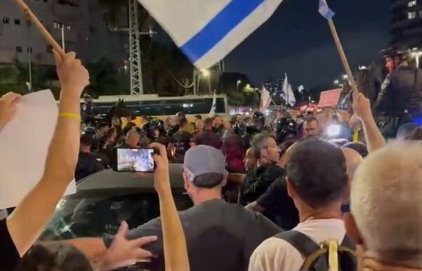מגינים חוסמים רכב משטרה אליו הוכנס שחר מור (זהירו), אחיינו של החטוף אברהם מונדר ז"ל, שנעצר במהלך הפגנה לשחרור החטופים בתל אביב (צילום: אורן דגן)