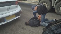 שוטר עוצר את אחד החשודים ברצח בתל שבע (צילום: דוברות המשטרה)