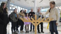 לאה גופר, מנהלת ההזמנות באתר אגמון החולה, מדליקה נר שלישי של חנוכה באגמון החולה. משמאל: נעמה לוינבוק, מדריכת טיולים בקק"ל (צילום: מיכאל גלעדי)