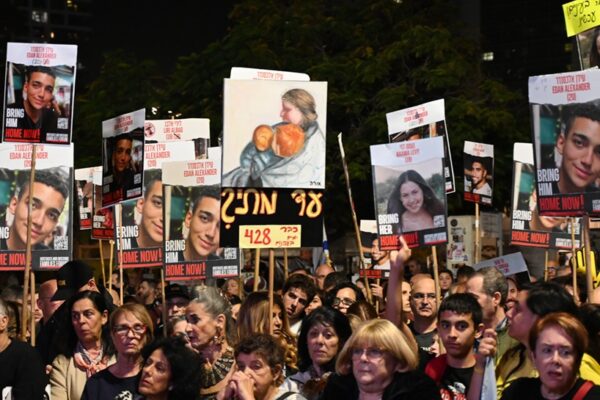 משתתפים בעצרת בכיכר החטופים. באחד השלטים מוצג ציור של החטופה שירי ביבס עם ילדיה כפיר ואריאל, שחטופים אף הם  (צילום: פאולינה פטימר)