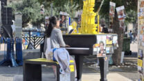 אישה מנגנת על הפסנתר שהוצב בכיכר החטופים בקריאה להשבת החטוף אלון אהל (צילום: הדס יום טוב)