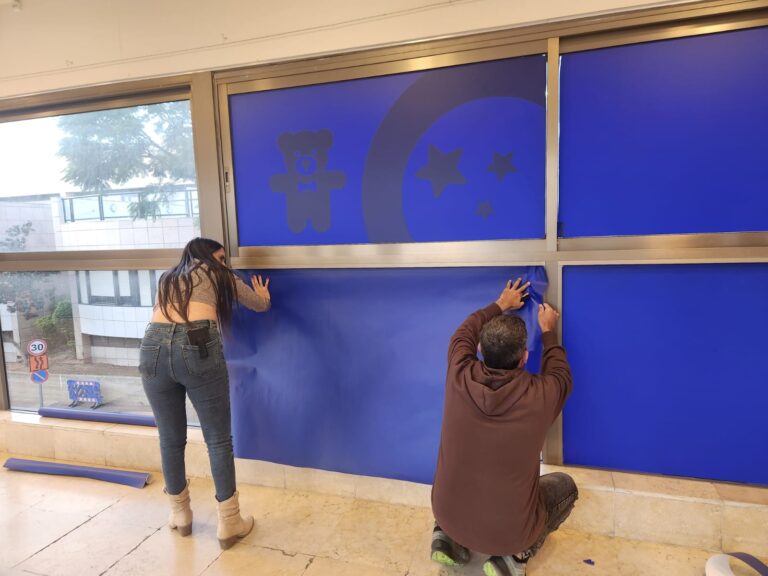עובדי המרכז הרפואי שיבא מכסים חלונות במתחם שמיועד לחטופות ולחטופים, לקראת הגעתם (צילום: דפנה איזברוך)