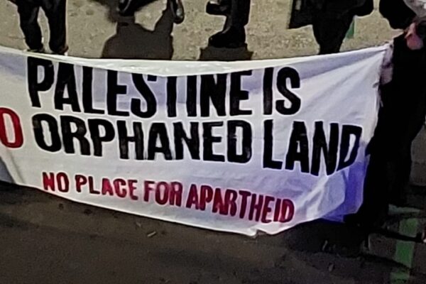 مظاهرة خارج الحفلة والعرض في برشلونة. كُتب على اللافتة: "فلسطين ليست أرضًا يتيمة، لا يوجد مكان للفصل العنصر (الابرتهايد)" (تصوير : من داخل مواقع شبكات التوصل الاجتماعي، استخدام وفقًا للبند 27 أ من قانون حقوق النشر)
