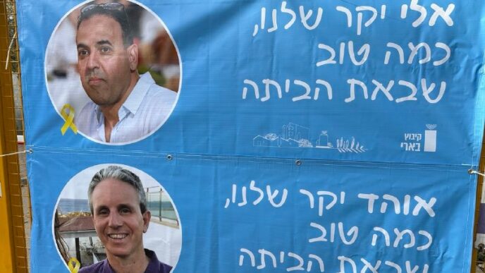השער לקיבוץ בארי – עם שלטים לקראת שובם של חברי הקיבוץ אלי שרעבי ואוהד בן עמי (צילום: רשתות חברתיות לפי סעיף 27 א')