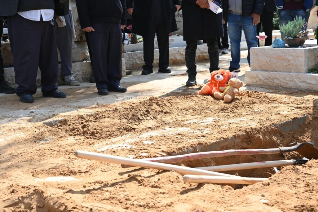 בובות על קברם הטרי של אריאל, כפיר ושירי ביבס, שנרצחו בשבי חמאס (צילום: איתן אונר)