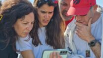 חברי ניר עוז צופים בחברי הקיבוץ סשה טרופנוב, יאיר הורן ושגיא דקל חן משתחררים מהשבי (צילום: הדס יום טוב)